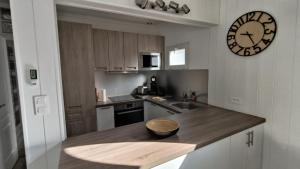 eine Küche mit einer Uhr an der Wand und einer Schüssel auf einer Theke in der Unterkunft L escale du Bassin 800 m de la plage 3 pers in Andernos-les-Bains