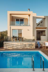 a villa with a swimming pool in front of a house at Dolce Luxury Villas in Psarou
