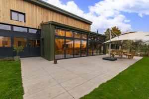 a patio with an umbrella next to a building at Dragons Barn with Hot Tub in Great Malvern