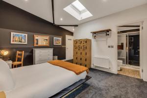 Un dormitorio con una cama grande y un baño. en Dragons Barn with Hot Tub, en Great Malvern
