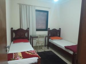 two beds in a room with a table and a window at HOTEL CENTER Ribeirão in Ribeirão Preto