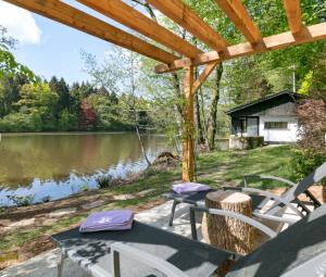 a patio with a table and chairs next to a lake at La Douceur de l'Oise in Momignies