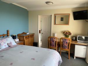 a bedroom with a bed and a desk with a microwave at Citrus Grove in Nelson +44 photos