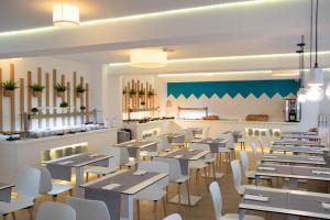 Un restaurante con mesas de madera y sillas blancas. en BLUESEA Arenal Tower Adults Only, en El Arenal