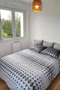una camera da letto con un letto bianco e nero e una finestra di Petite maison avec jardin a Landrévarzec