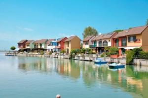 a row of houses next to a river with boats at Charming villa with garden and views in Albarella in Isola Albarella