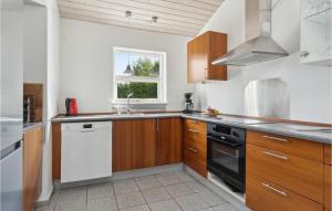 a kitchen with wooden cabinets and a white dishwasher at Beautiful Home In Væggerløse With Sauna in Bøtø By