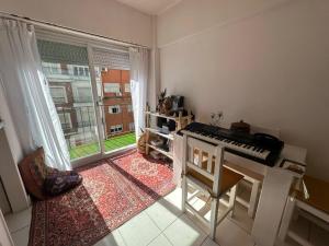 un salon avec un piano et une grande fenêtre dans l'établissement Departamento centro Mar del Plata-1 cuadra del mar- monoambiente-balcón calle., à Mar del Plata