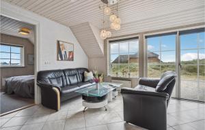 ein Wohnzimmer mit Ledermöbeln und einem Bett und Fenstern in der Unterkunft Pet Friendly Home In Ringkøbing in Nørre Lyngvig