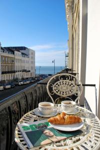 a table with two cups and a plate of food on a balcony at Portland Place in Brighton & Hove