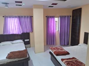 a bedroom with two beds and purple curtains at Hotel Ruby in Ujjain