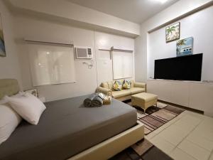 a living room with a bed and a flat screen tv at JK Suites Cheer B126 in Marilao