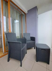 two chairs and a table in a room with windows at RentPlanet - Apartament Bałtycka in Kołobrzeg
