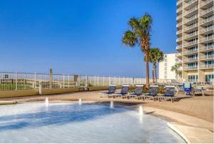 a pool with chairs and palm trees on a beach at Lighthouse 1115 Condo on the beach 3BR 3BA in Gulf Shores