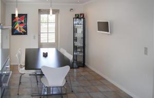 a dining room with a black table and white chairs at Three-Bedroom Holiday Home In Blavand in Blåvand