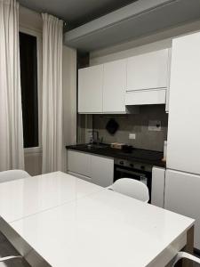 een keuken met witte kasten en een tafel en stoelen bij 10 min da Navigli e centro, nuova e luminosa oasi 1p in Milaan