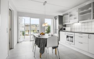 a white kitchen with a table and chairs in it at Holiday Home Næsvej Assens Xii in Assens