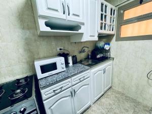 uma pequena cozinha com armários brancos e um micro-ondas em Relaxing Apartment with garden view in New Cairo em Cairo