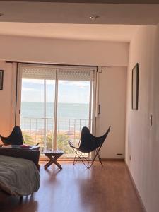 a bedroom with a bed and chairs and a large window at Mar Del Plata Loft in Mar del Plata