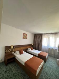 a hotel room with two beds and a window at Garsoniere Aby in Turnu Măgurele +3 photos