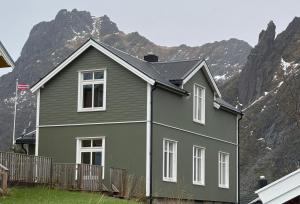 una casa verde con una montaña en el fondo en Svolvær Villa i Lofoten, en Svolvær
