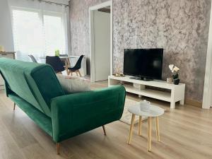 a living room with a green couch and a tv at Rainbow Apartments in Floreşti