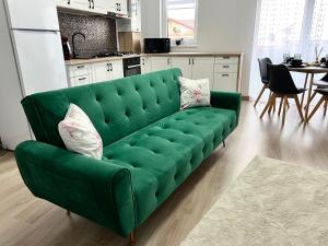 a green couch in a kitchen with a table at Rainbow Apartments in Floreşti