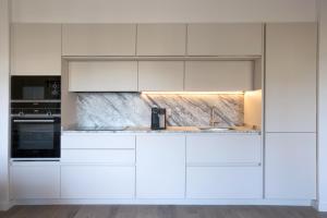 a kitchen with white cabinets and a sink at The Diagonal Suites by Sweett in Barcelona