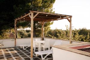 drewniana pergola z białymi krzesłami i stołami na patio w obiekcie Casette Masseria La Camardia w mieście Sava +37 zdjęć