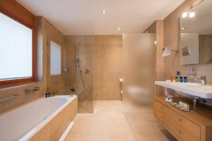 a bathroom with a tub and a shower and a sink at Chalet Shalimar in Zermatt