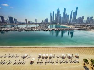 einen Strand mit Stühlen und Sonnenschirmen vor einer Stadt in der Unterkunft Atlantis View 1BR with Beachfront Access and Balcony in Dubai