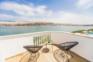 a balcony with two chairs and a view of the water at Hotel Plaza in Pag