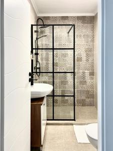 Un baño con lavabo y ducha de cristal. en Rainbow Apartments, en Floreşti