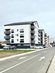 un edificio de apartamentos con coches estacionados al lado de una carretera en Rainbow Apartments, en Floreşti