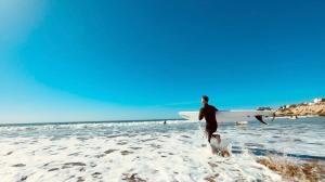 a man walking on the beach with a surfboard at Taghazout surf house in Taghazout