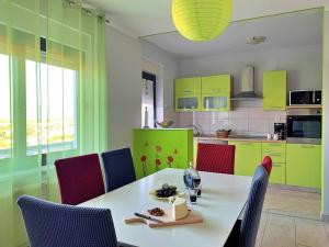 kuchnia z białym stołem z krzesłami i zielonymi szafkami w obiekcie Apartment Rozi w mieście Šilo