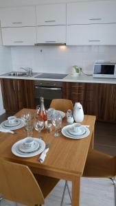eine Küche mit einem Holztisch mit Tellern und Weingläsern in der Unterkunft Centro apartamentai - Vingio apartamentai in Vilnius