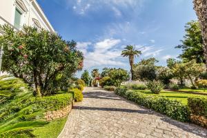 a cobblestone path in a garden with a palm tree at Villa Irlanda Grand Hotel in Gaeta