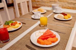 a table with plates of food and glasses of orange juice at Hotel San Gabriel in São Paulo