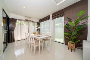 a dining room with a white table and chairs and a plant at Laguna pool house in Phuket Town