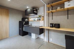 a kitchen with a black refrigerator and a sink at Riverside Sauna Base Conpeki in Taniai