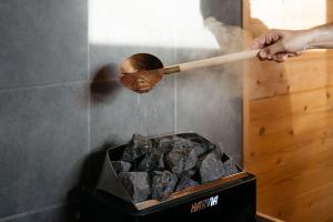 a person holding a wooden spoon over a box of coal at Riverside Sauna Base Conpeki in Taniai