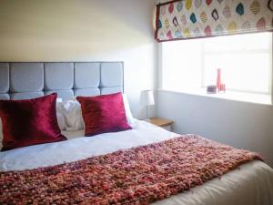 een slaapkamer met een groot bed met rode kussens bij Chic Clock Tower with Gardens Close to Beaches in Johnston