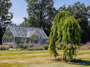 een kas in een veld met een boom ervoor bij Chic Clock Tower with Gardens Close to Beaches in Johnston