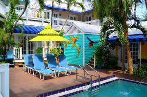a pool with a blue umbrella and blue chairs at La Te Da - Adult Only, 21 or older in Key West
