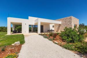 a white house with a stone wall at Quintessenza by Perle di Puglia in Torre Vado