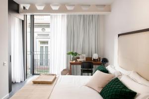 a hotel room with a bed and a desk and a window at The Passage Homes - Simaba Group in Barcelona