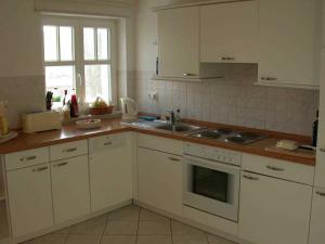 Una cocina con gabinetes blancos y un fregadero. en Zinnowitz Ferienwohnung im Haus Seeblick, en Zinnowitz