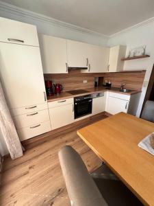 a kitchen with white cabinets and a wooden table at Sonnhang Apartment Unterkofler in Sankt Johann im Pongau