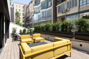 a row of yellow chairs and tables on a balcony at The Passage Homes - Simaba Group in Barcelona